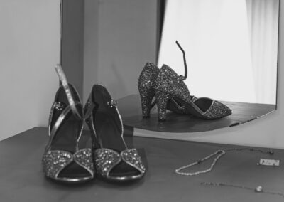 photo souliers posés sur une table sur la quelle un miroir est posé avec en arrière plan une robe de mariée